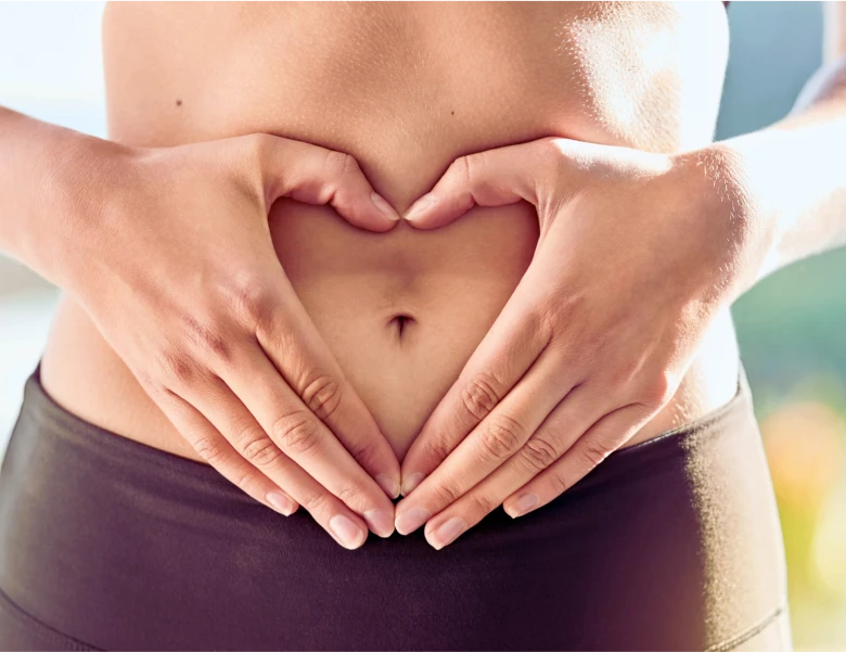 a woman holding her stomach with her hands in the shape of a heart